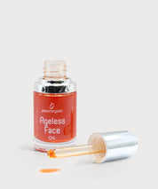 Offene Glasflasche „Ageless Face Oil“ mit silberner Pipette, orangefarbenes Gesichtsöl sichtbar, ein Tropfen Öl auf hellem, neutralem Untergrund.