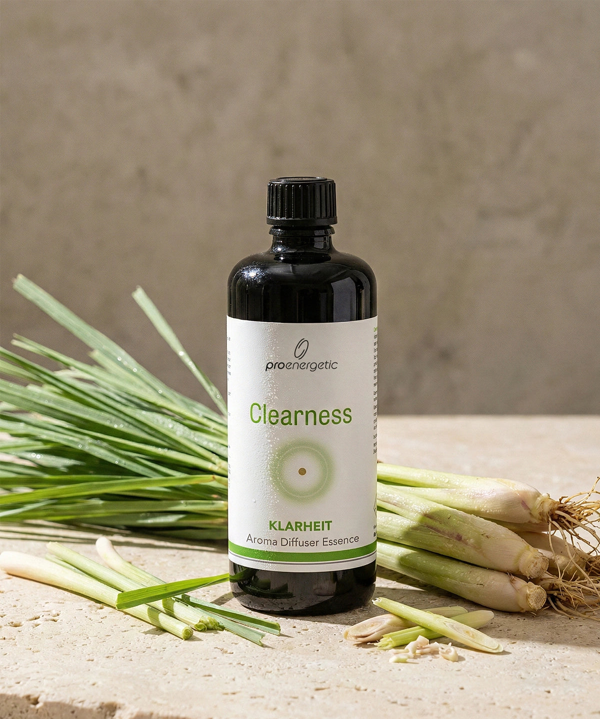 Aroma Diffuser Essence Clearness in dunkler Glasflasche mit Etikett, platziert neben frischem Zitronengras