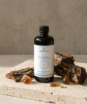 Aroma Diffuser Essence Serenity in dunkler Glasflasche mit Etikett, arrangiert mit Copaiba Harz und Holzstücken