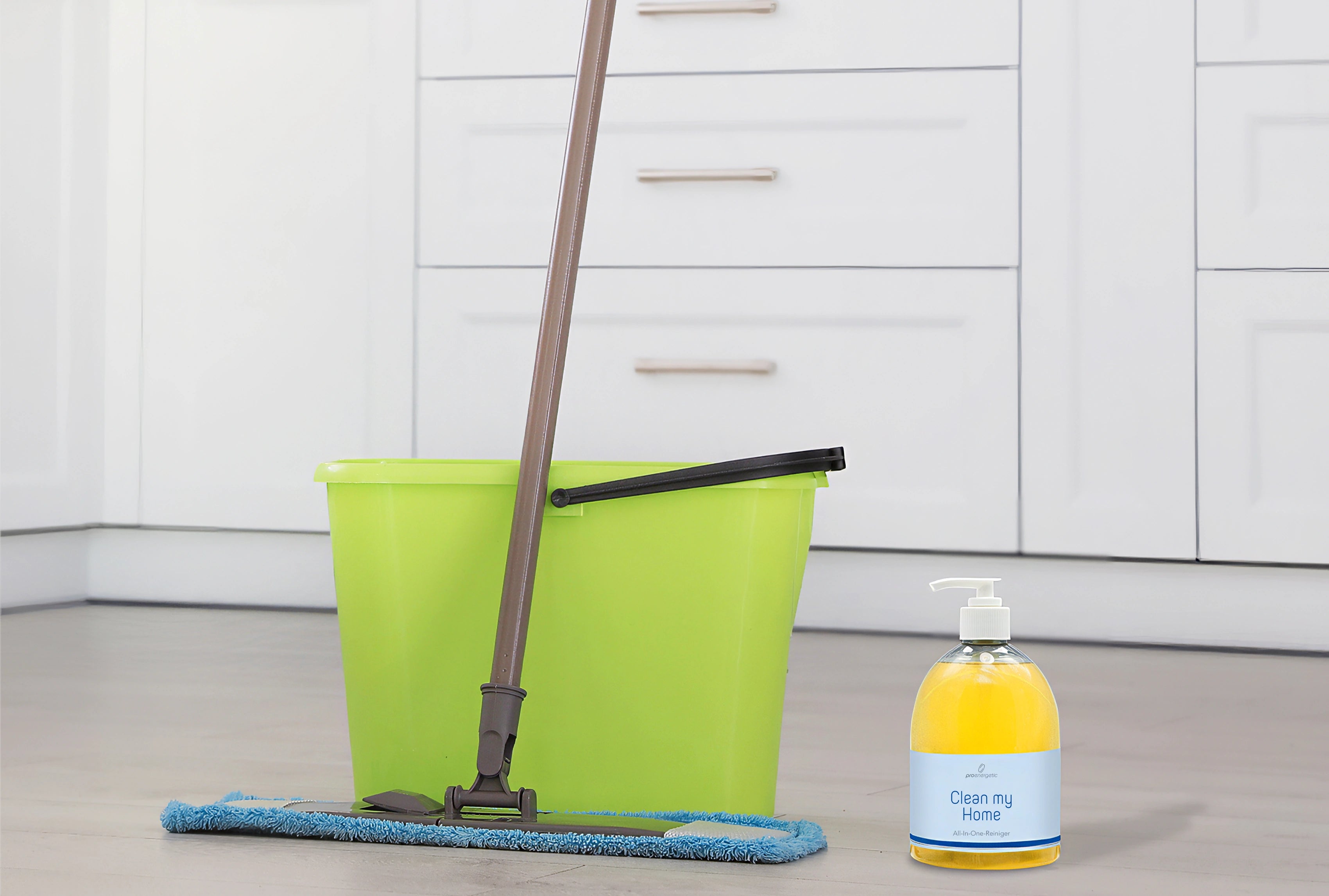 Boden wird mit Wischmopp gereinigt, daneben stehen ein grüner Putzeimer und die Clean my Home Pumpflasche in einer Küche