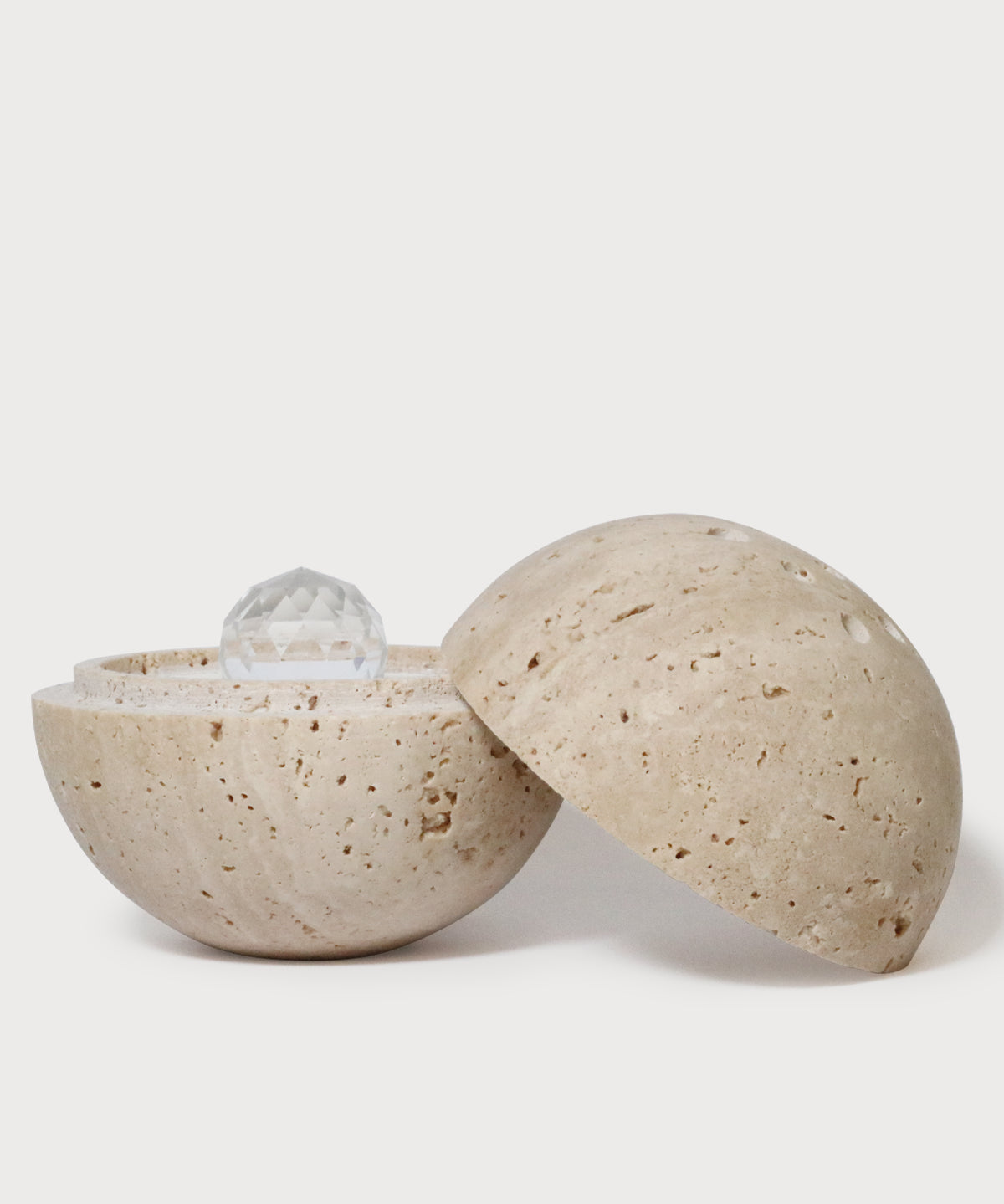 Geöffnete Dormea Kugel von ProEnergetic aus beigefarbenem Stein mit Kristall im Inneren auf hellem Hintergrund.