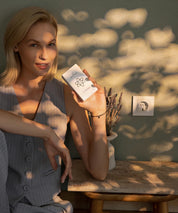 Frau sitzt an einem Tisch im Innenraum und hält das weiße ProEnergetic E-Protect S230 Steckgerät in der Hand