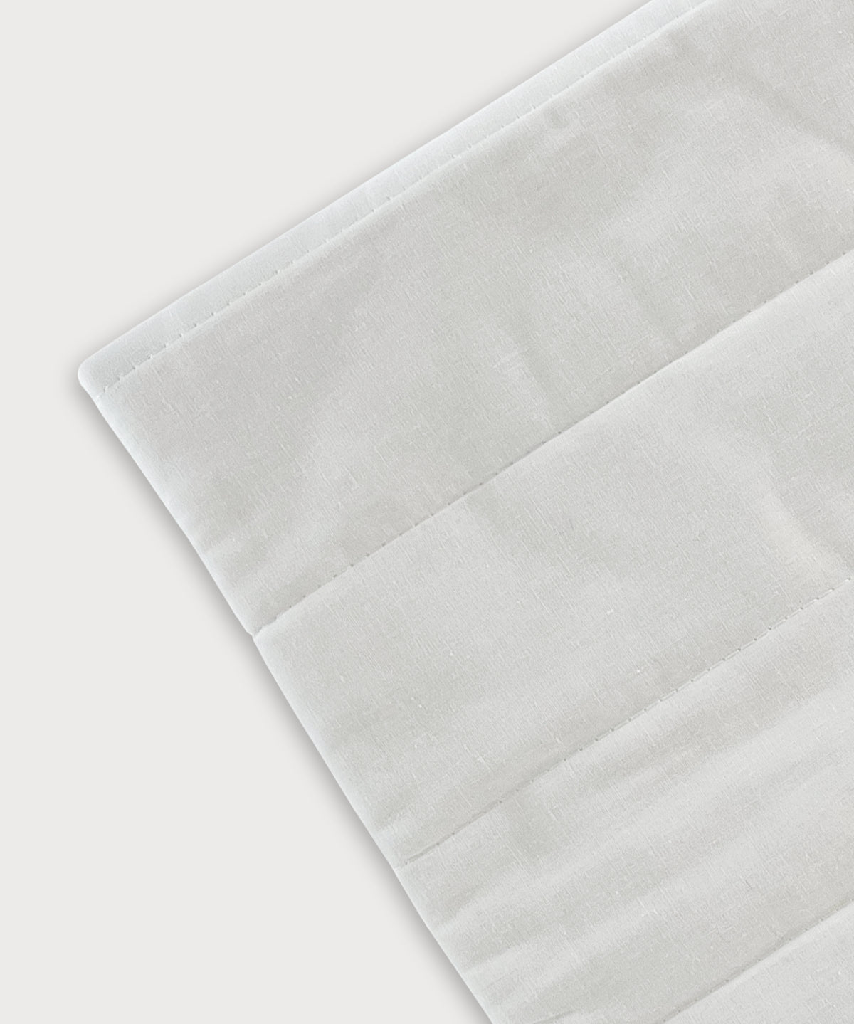 Detailansicht des Grounding Relax Pad mit weißer Textiloberfläche und fein gearbeiteten Nähten auf hellem Hintergrund
