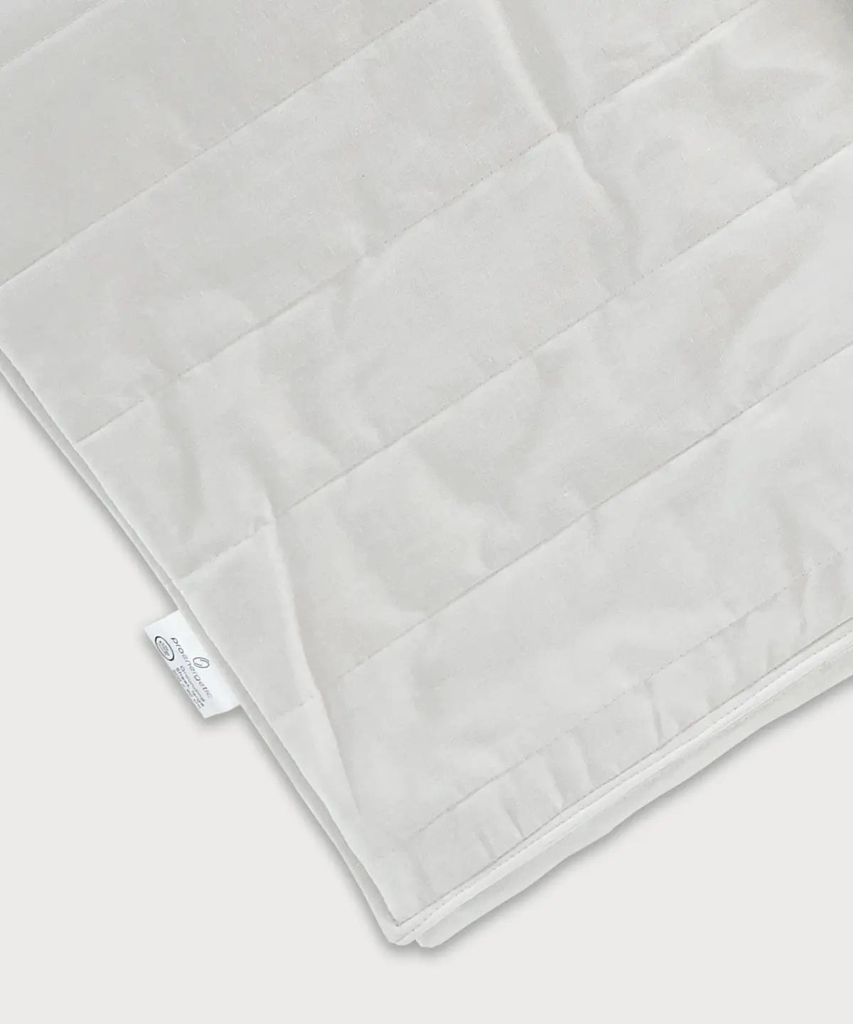 Detailansicht der Grounding Sleep Mat mit weißer Textiloberfläche, gestepptem Muster, integrierten Silberfasern und sichtbarem Etikett am Rand