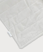 Detailansicht der Grounding Sleep Mat mit weißer Textiloberfläche, gestepptem Muster, integrierten Silberfasern und sichtbarem Etikett am Rand