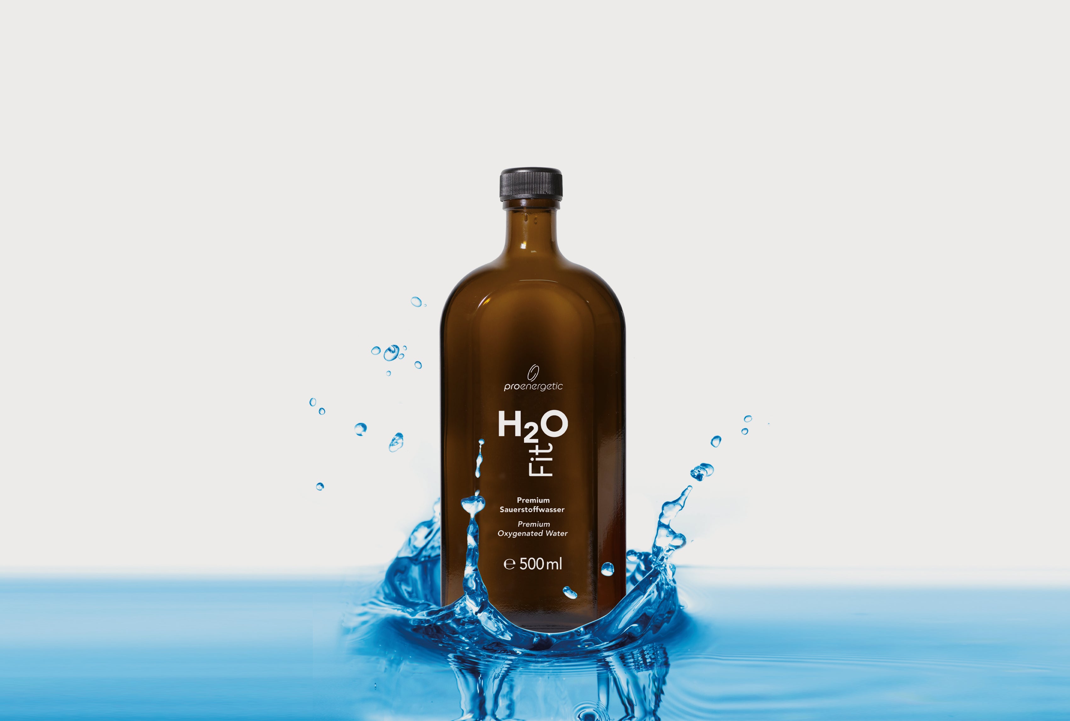 Braune Glasflasche H2O Fit von ProEnergetic mit schwarzem Schraubverschluss in spritzendem Wasser auf hellem Hintergrund.