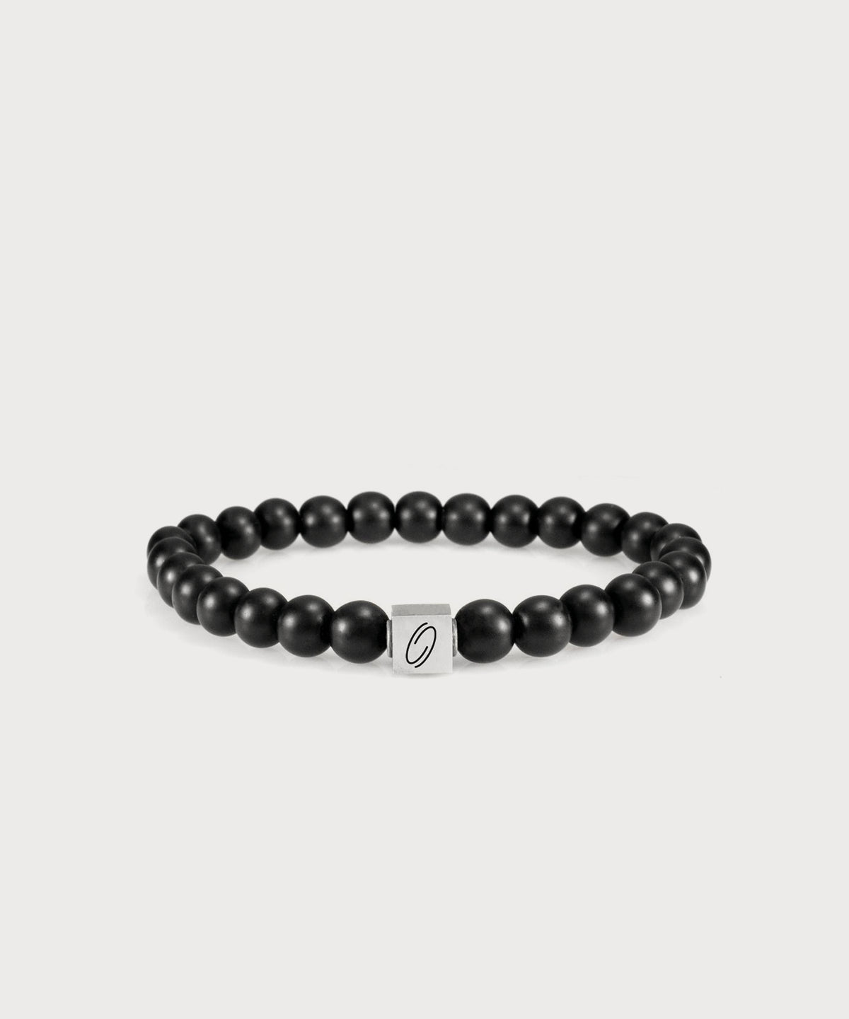 Black “I AM” Energy Bracelet with matte beads and a silver-colored logo element on a light-colored background
