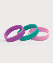 Drei ProEnergetic Kids Band Armbänder aus Silikon in Lila, Türkis und Rosa mit glatter Oberfläche und dezent eingeprägtem Markenlogo auf hellem Hintergrund