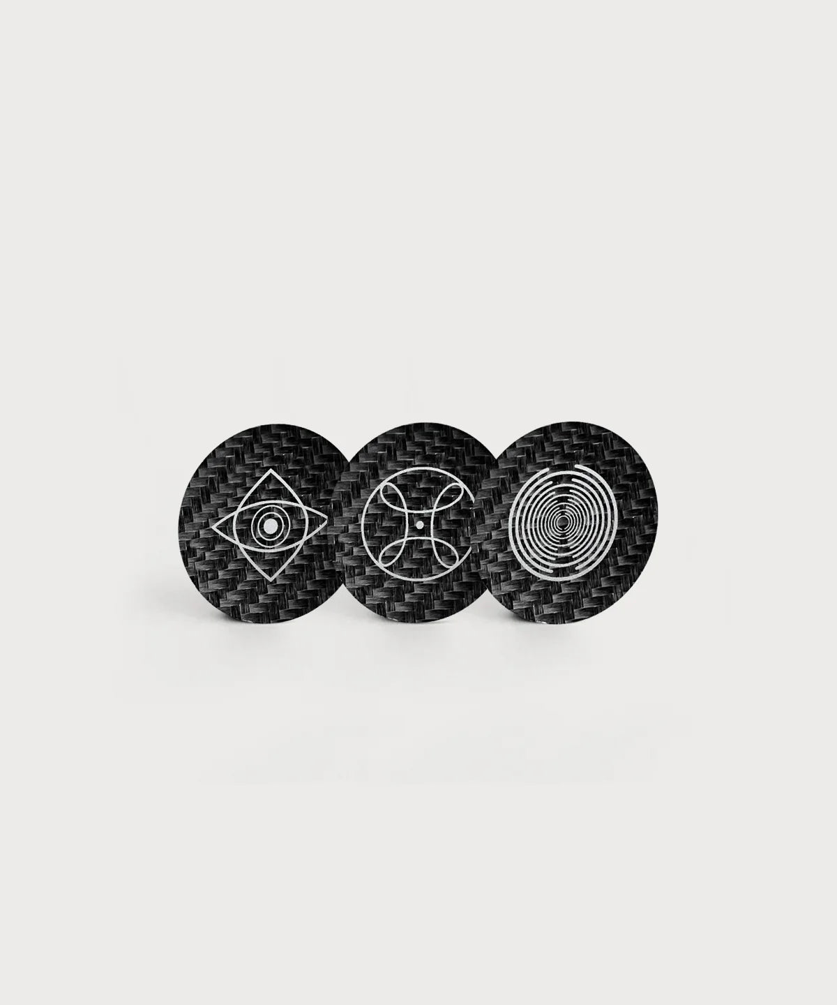 Drei runde schwarze Love & Light Chips von ProEnergetic mit Carbonstruktur und unterschiedlichen geometrischen Symbolen in Weiß auf hellem Hintergrund.