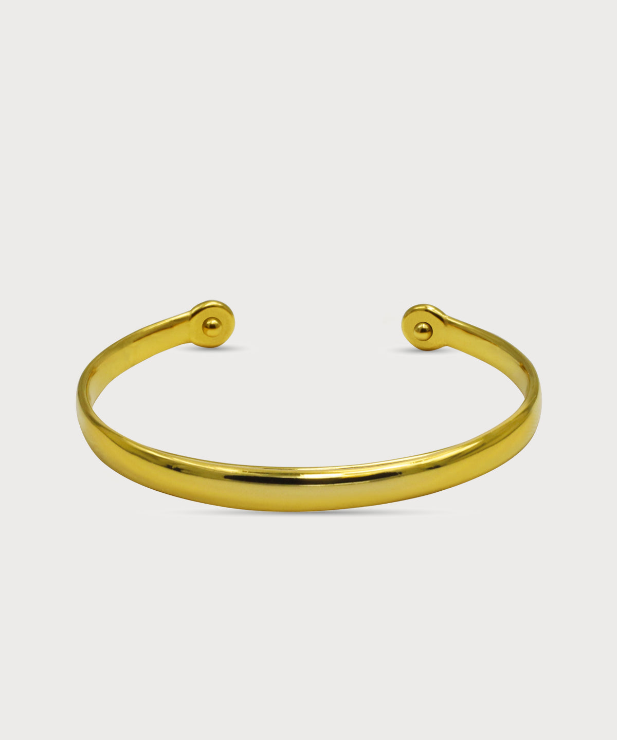 Goldfarbener Lunara Cuff Armreif mit glatter polierter Oberfläche und offenen Enden vor hellem Hintergrund