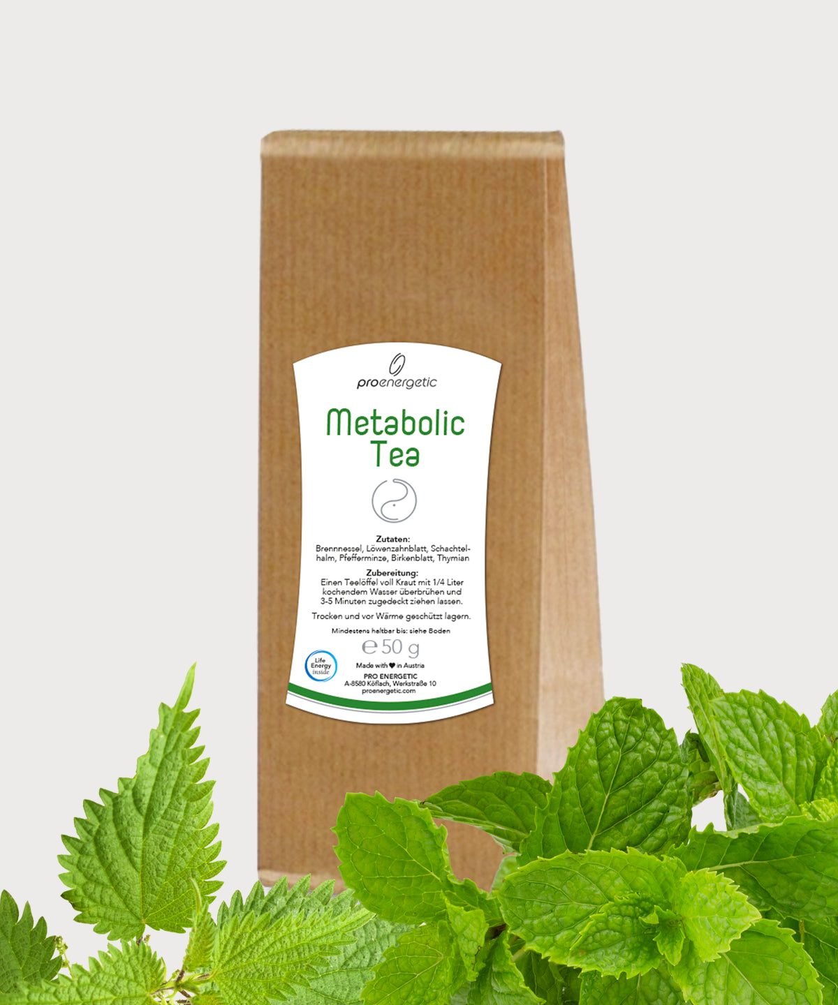 Braune Papierverpackung Metabolic Tea von ProEnergetic mit weißem Etikett, im Vordergrund frische grüne Blätter auf hellem Hintergrund.
