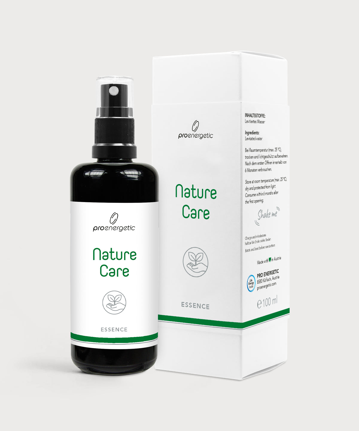 Dunkle Sprühflasche Nature Care Essence neben weißer Produktverpackung auf hellem Hintergrund.