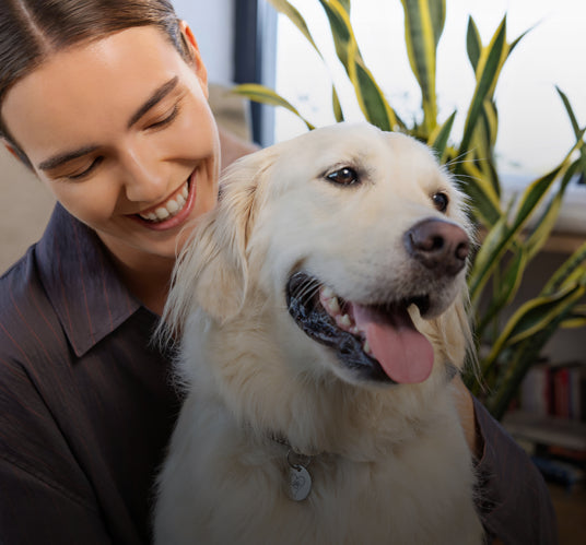 Frau lächelt, während sie einen Hund hält, der sichtbare den Pet Tag trägt