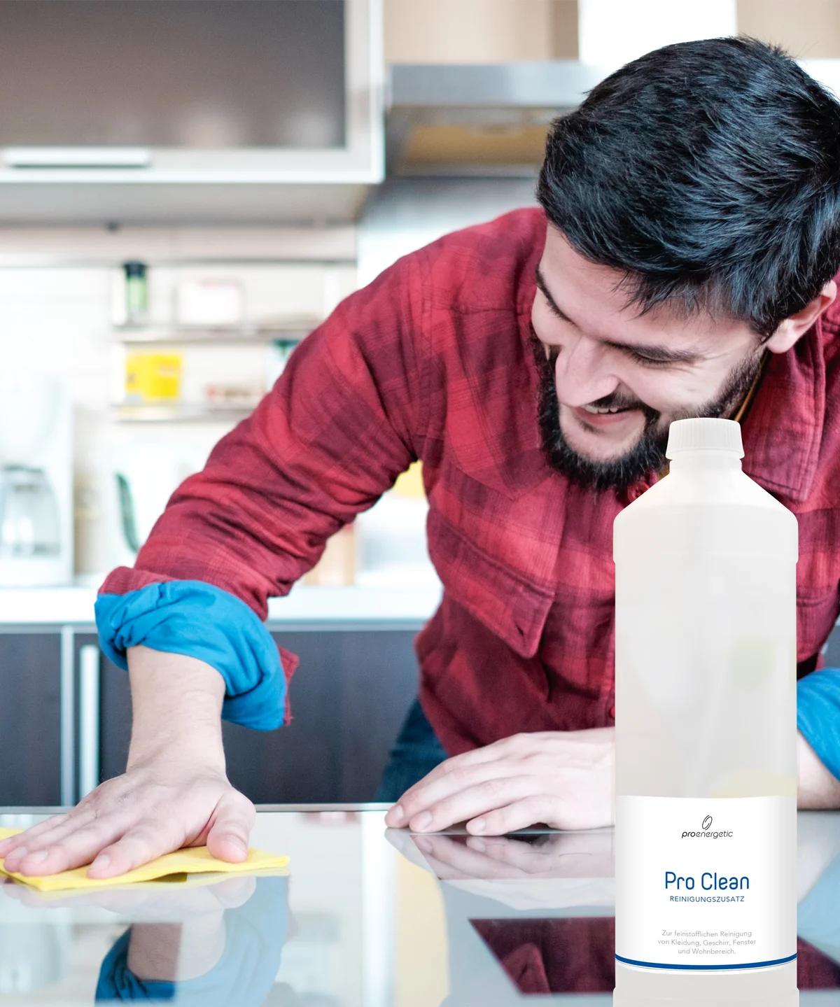 Person reinigt eine glatte Oberfläche mit einem Tuch, daneben steht die Pro Clean Flasche in einer Küchenumgebung