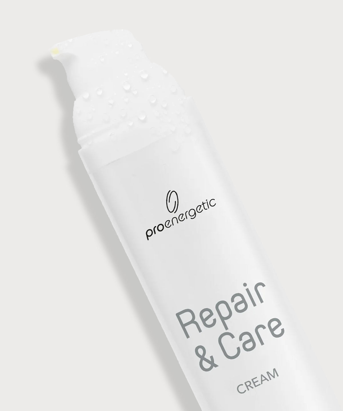 Schräg liegender ProEnergetic Repair & Care Cream Spender mit Wassertropfen auf dem Deckel.
