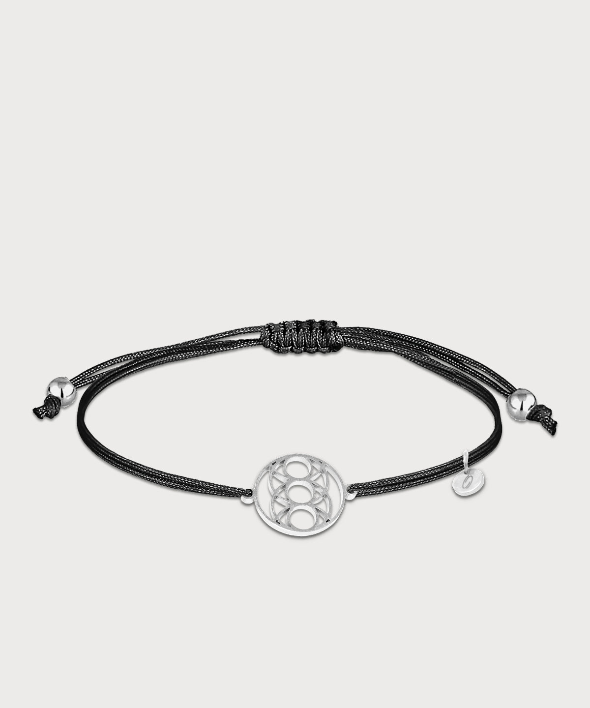 Black “Seed of Happiness” bracelet with a silver-colored symbol and an adjustable strap on a light-colored background