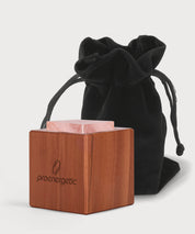 Holzwürfel mit ProEnergetic Logo und rosa Rosenquarz Stein vor schwarzem Stoffbeutel.