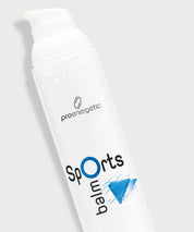 Detailaufnahme der weißen „Sports Balm“-Pumptube mit proenergetic Logo, blauem Grafikakzent und feinen Wassertropfen auf der Oberfläche, schräg vor hellem Hintergrund.