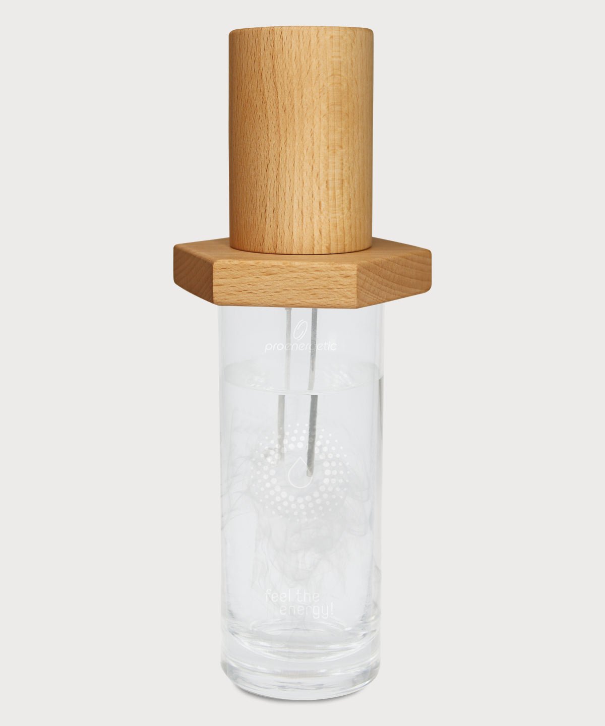 Vital Energizer von ProEnergetic. Holzaufsatz mit Metallstäben auf transparentem Glas mit eingraviertem ProEnergetic Logo.